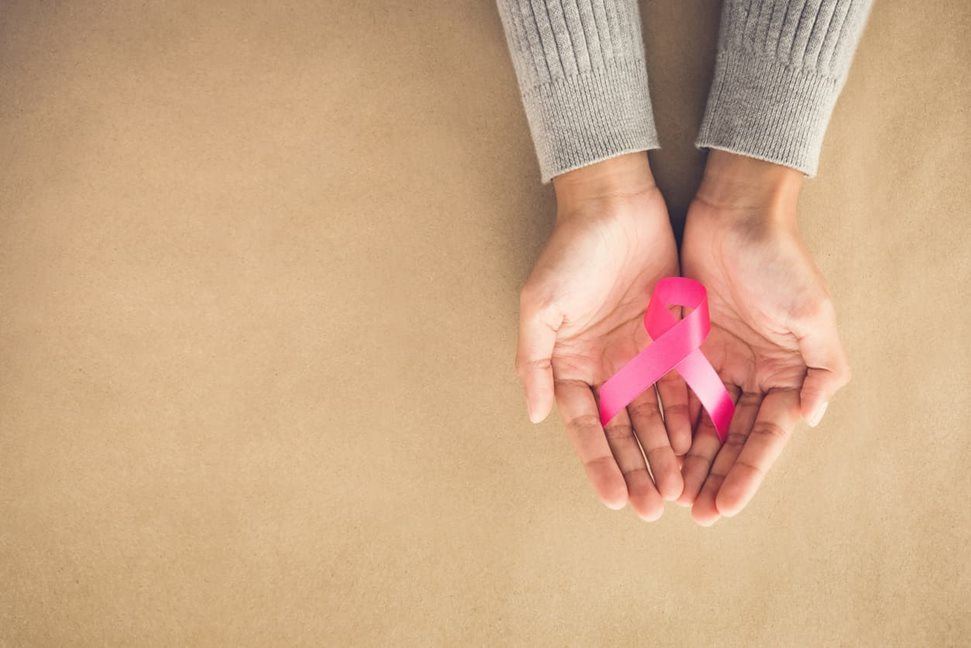 Woman holding symbolic pink ribbon in her palms
