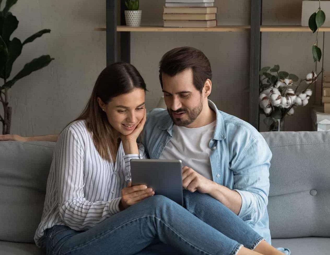 Couple sitting on couch looking at tablet device