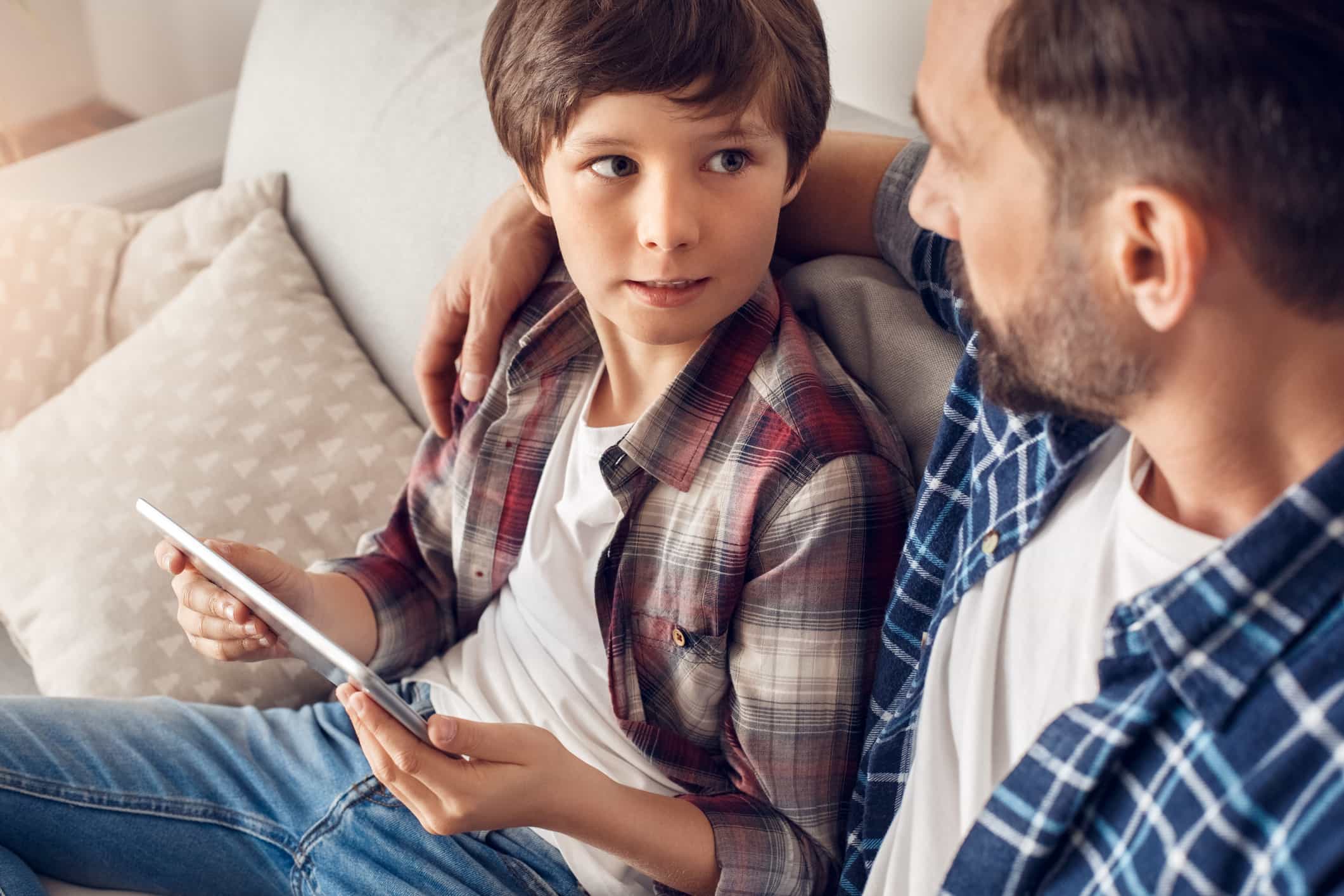 Boy and dad using a tablet device on the couch