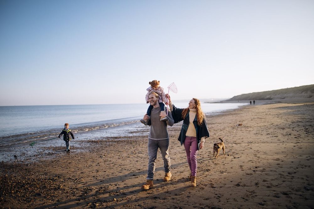 young family walking on beach